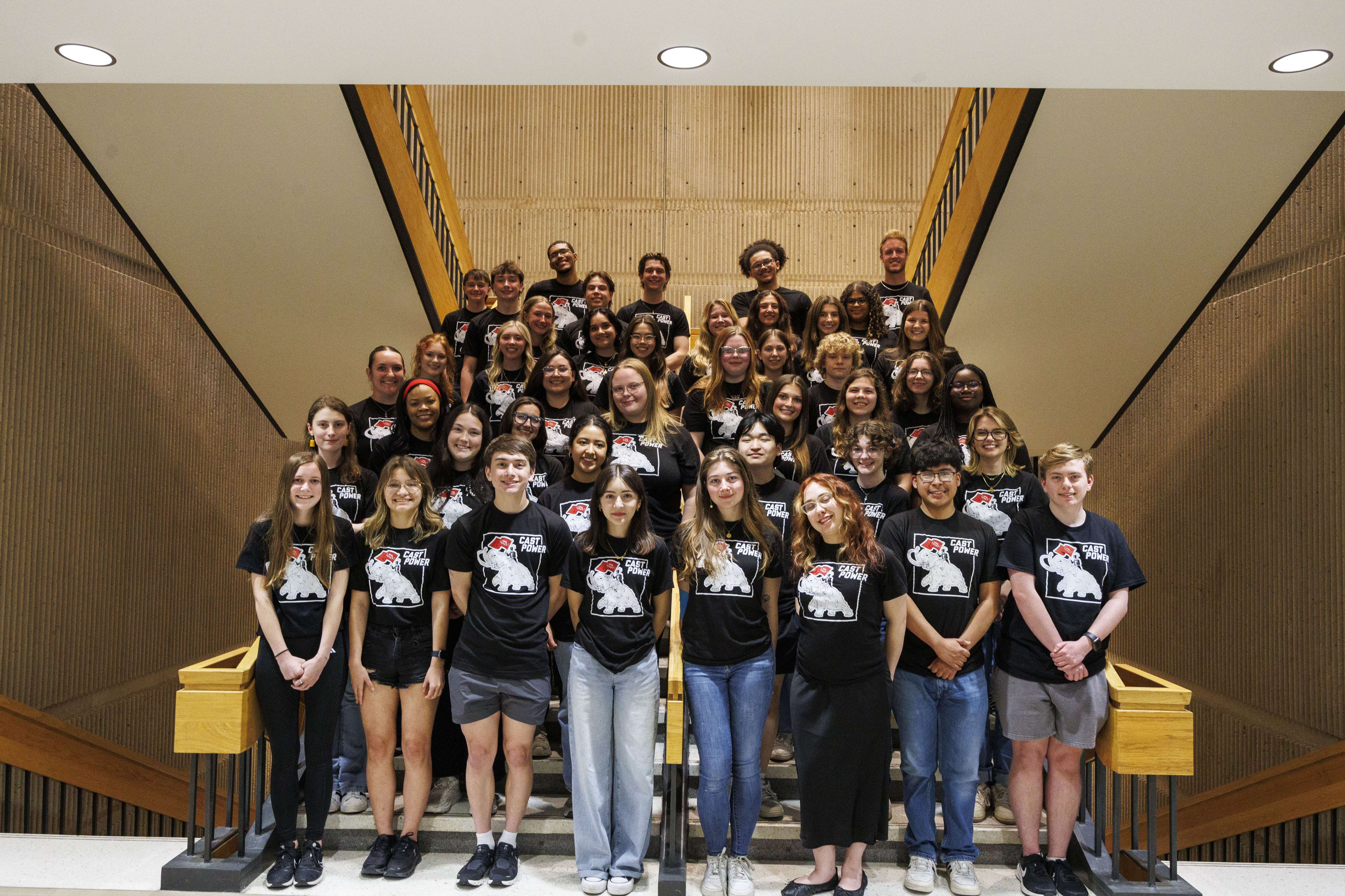 Group of students standing on staircase in matching shirts. 