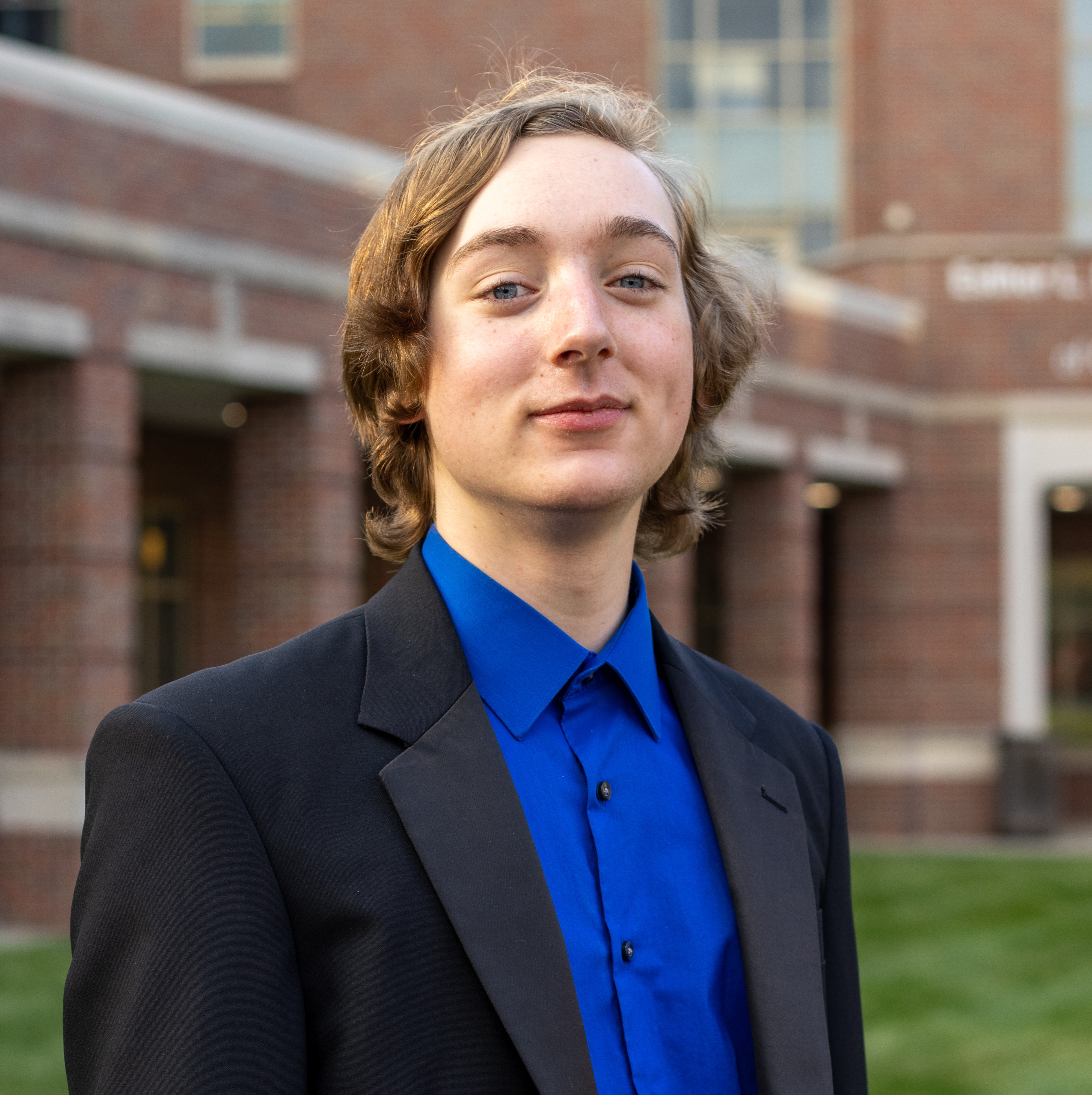 Photo of Henry smiling in blue shirt and black suitcoat 