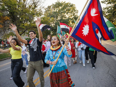 Group of International students walking in a parade waving different flags.
