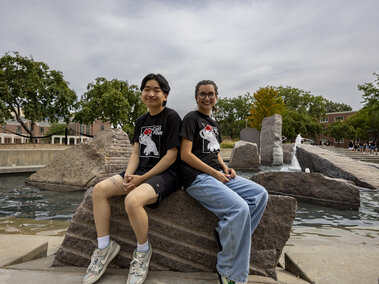 Two students sitting on a rock by the Union fountain.